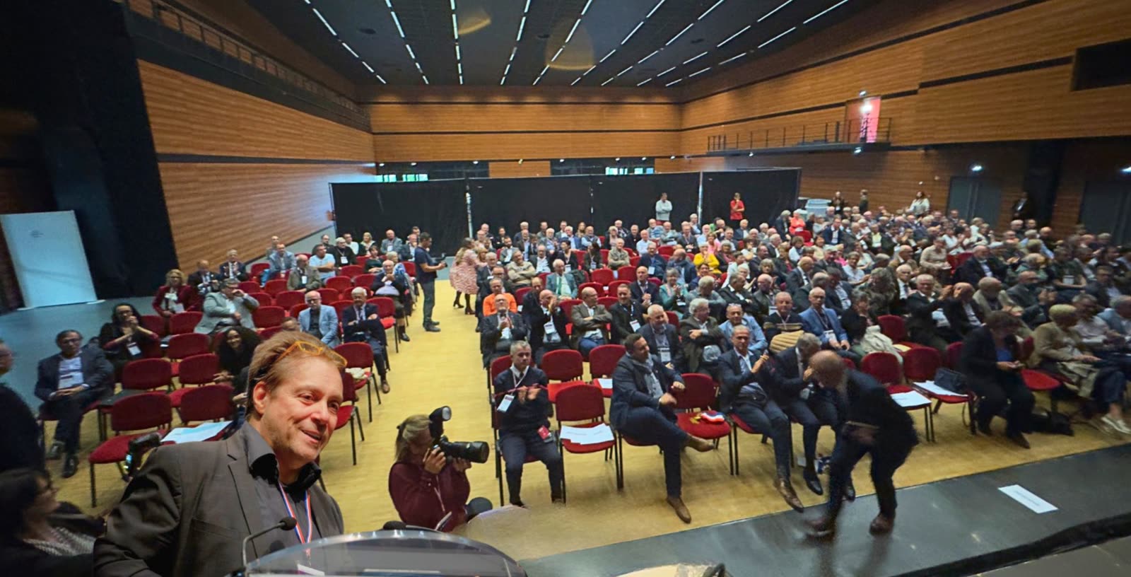 Alexandre Stopnicki au pupitre devant une salle comble de maires